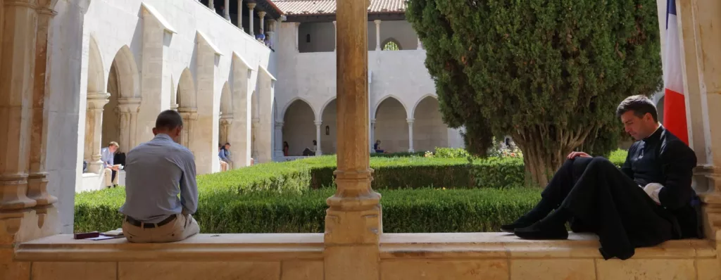 prêtre et jeune dans un cloître méditant