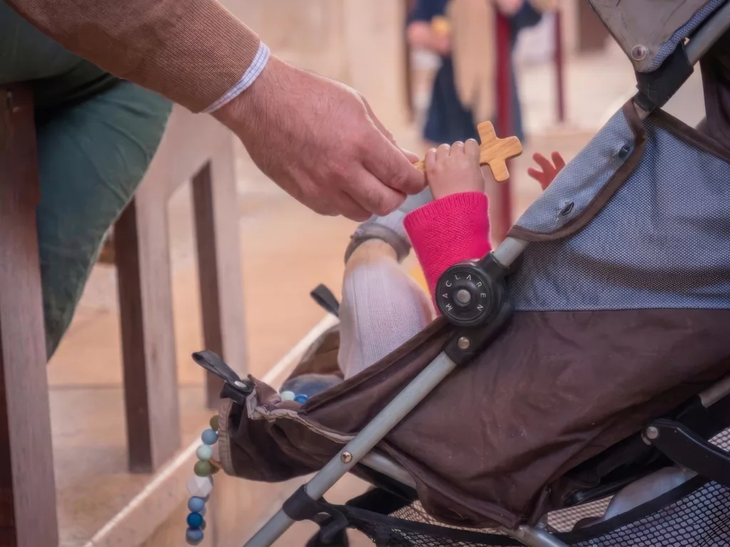 une maman donne une croix à son bébé
